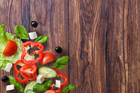 木制背景上的飞行沙拉红色西红柿,胡椒,奶酪,罗勒,黄瓜橄榄图片