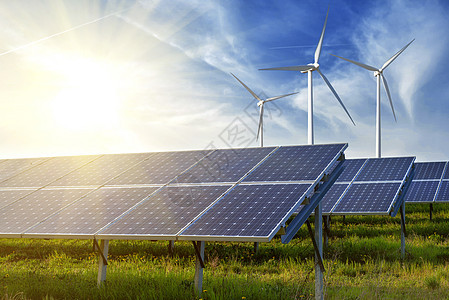 日落时蓝天下的太阳能电池板风力发电机图片