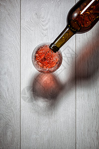 红酒白木桌上的瓶子里倒入璃杯的风景图片
