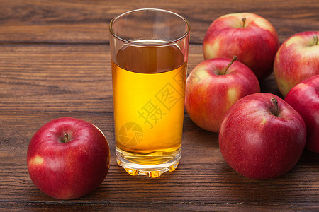 木制背景上的杯苹果汁红苹果图片