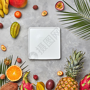 多汁成熟的热带水果,菠萝,木瓜,芒果,绿色的棕榈叶空的白色方形盘子灰色的混凝土背景上,文字的平躺方形白色图片