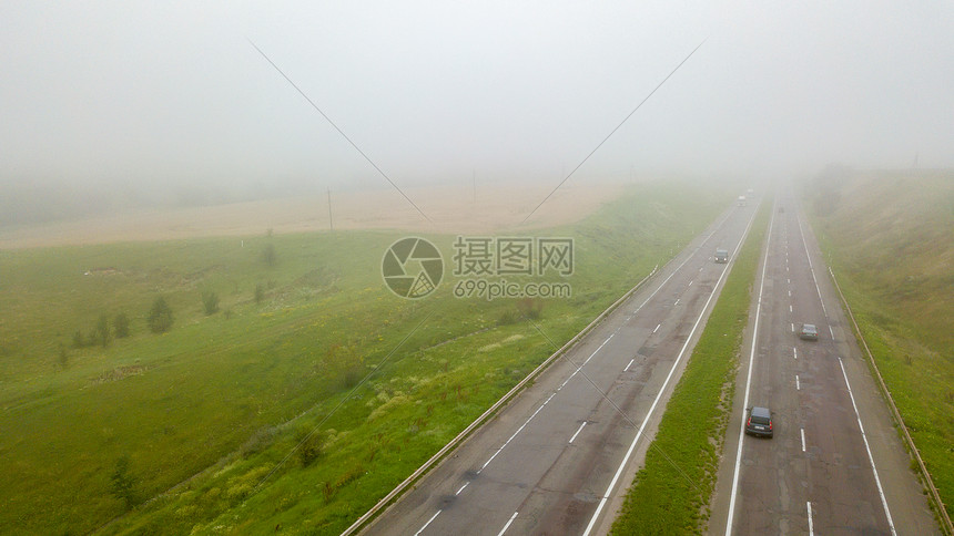鸟瞰照片,无人机,景观视野的田野道路与汽车雾中鸟瞰雾状道路的全景,汽车环绕着田野无人机的照片图片