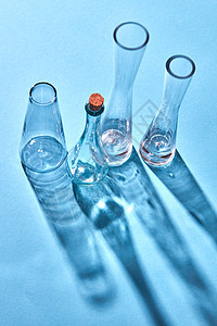 璃透明化学实验室璃空阴影反射表的蓝色背景,放置文字实验室蓝色纸背景上的璃空瓶,长的阴影反射图片