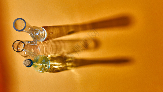 眼镜空着,黄色背景上的表上阴影反射,放置文本研究实验室测试璃瓶科学医学背景黄色纸上三个璃空花瓶的顶部视图片