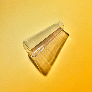 个装反射阴影的璃瓶空黄色背景上,放置文本用于实验的实验室工具实验室的个透明的璃花瓶空个纸背图片