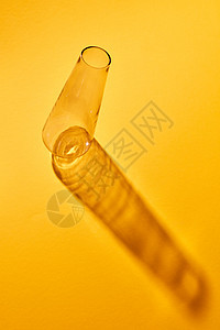 个透明的璃瓶空躺纸背景上,抽象的阴影,放文字的位置实验室化学工具实验室璃透明瓶,反射黄色纸背景图片