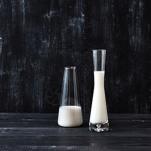 白色牛奶黑色背景的眼镜上,文字的地方节省牛奶的技术两杯牛奶放黑色的木制深色桌子上天然机乳制品图片