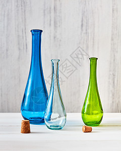 绿色,蓝色透明璃瓶与塞子灰色背景与节约自制产品的三个彩色璃瓶与塞子,以节省橄榄油灰色背景,张桌子图片