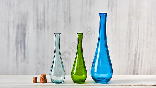瓶子绿色的,蓝色的,透明的,站灰色的桌子上,背景浅灰色的,文字的地方节省自制产品的三个彩色璃瓶,同大小,以图片