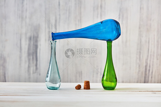 两个璃瓶站张桌子上,个蓝色的瓶子放,浅灰色的背景上软木塞节省自制产品的璃瓶空,以节省天然自制葡萄酒图片