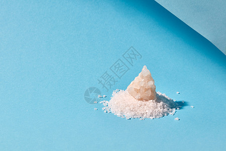 矿物海盐堆大水晶隔离蓝色背景上,堆晶体矿物盐张浅色的蓝色纸上,阴影图片