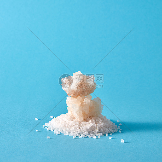海盐堆大水晶隔离个蓝色的背景上,矿物盐的晶体堆张浅蓝色的纸上,阴影