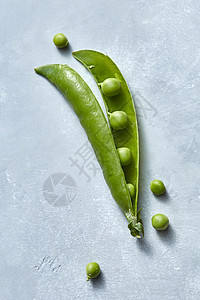 天然素食清洁生食绿色豌豆的棍子灰色的桌子上,顶部的景色天然机豌豆的荚开放的,灰色的背景上小的球形颗粒图片