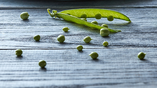 天然素食清洁生食绿色豌豆的棍子灰色的木制桌子上,健康纯素机饮食机绿色豆荚打开灰色的木制桌子上烹饪沙拉图片