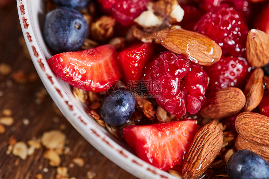 饮食自制的天然早餐与新鲜的机成分浆果,格兰诺拉,杏仁,坚果个白色碗木制桌子上健康素食新鲜机浆果,麦片,蜂图片