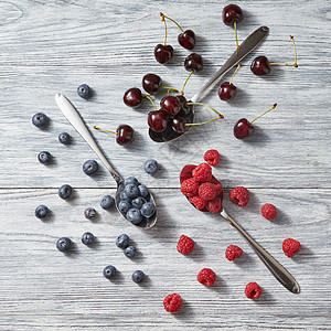灰色背景下新鲜夏季浆果的水果图案健康排饮食,抗氧化机水果的顶部视图新鲜采摘的蓝莓,樱桃,覆盆子灰色的木制背景图片