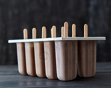 巧克力冰淇淋棒棒糖黑色木制桌子上的模子里冷的甜点咖啡冰淇淋塑料模具上的棍子上,深色的木制背景上夏日甜点图片