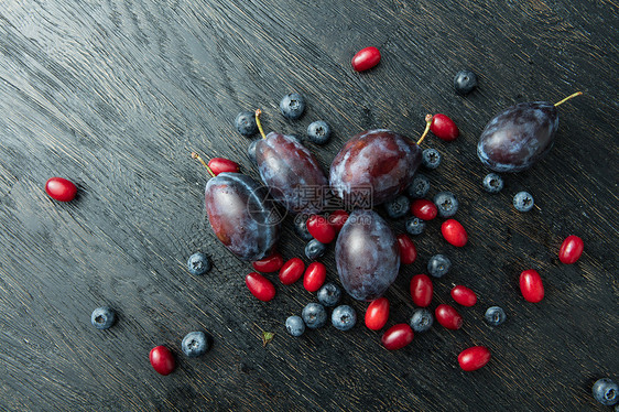 黑色木桌上的新鲜李子浆果蓝莓,李子茱萸图片