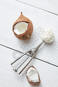 轻木背景上用椰子冰淇淋勺金属勺子里的椰子冰淇淋图片