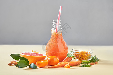 素食彩色橙色鸡尾酒机蔬菜,水果浆果纸背景与天然机健康食品的自制的橙色冰沙,胡萝卜,葡萄水果,沙棘,杏背景图片