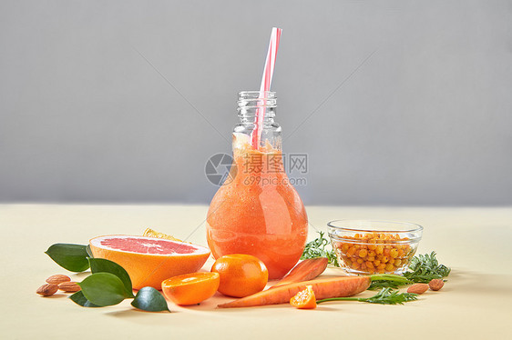 素食彩色橙色鸡尾酒机蔬菜,水果浆果纸背景与天然机健康食品的自制的橙色冰沙,胡萝卜,葡萄水果,沙棘,杏图片