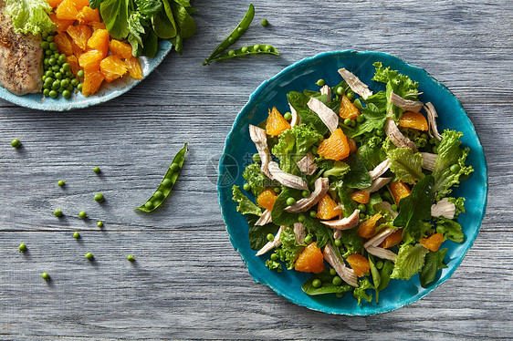 自制新鲜沙拉叶天然机成分健康饮食的顶部景观新鲜沙拉,橙色水果,绿色,鸡肉蓝色盘子上的灰色木制桌子平躺图片