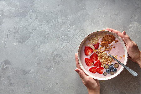 女的手着盘新鲜的酸奶浆果自制的麦片,背景灰色的混凝土,个健康早餐的风景自制的麦片酸奶图片