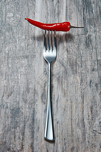 叉子与切碎的红色辣椒呈现灰色的旧木制背景上旧木桌上红色辣椒的金属叉子图片