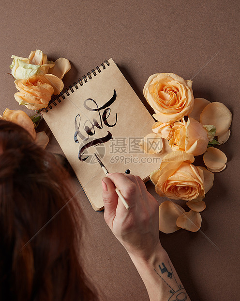 女人用刷子工艺纸上写爱字带玫瑰的情书图片