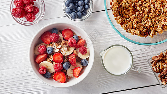 白色陶瓷碗与天然机浆果,水果,坚果,牛奶,穆斯利木背景天然健康机食品的俯视图自制的麦片盘子里,香蕉切片草图片