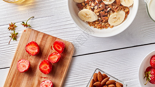 盘子上机麦片香蕉片,白色的木桌上,木板上草莓,盘子里杏仁健康早餐的机成分步步地饭厨房图片