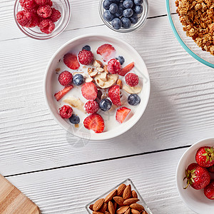 草莓牛奶白色桌子上白色陶瓷碗的顶部视图,天然的配料,用于准备美味健康的机早餐清洁机饮食的准备健康的机早餐麦片草背景