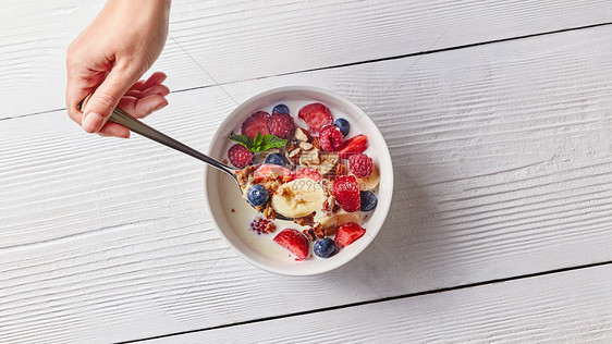 准备好美味健康的机早餐自制的天然食物白色桌子上的陶瓷白色碗里天然机健康饮食的白桌上的玉米片水果坚果牛图片