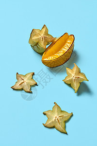 杨桃的整块异国水果蓝色背景上的星星水果,健康的食物平躺成熟的杨桃热带水果切片呈现蓝色背景与图片