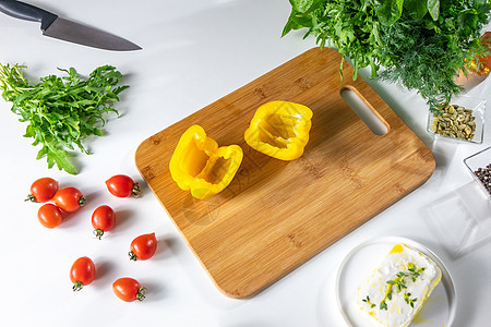新鲜西红柿,黄胡椒,茴香,鲁科拉,半山葵奶酪白色厨房桌子上,刀木板,步步地沙拉的风景套图片