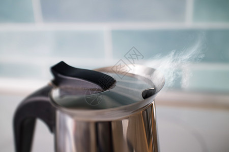 茶壶与沸腾的热气腾腾的饮用水蒸汽它的蓝色瓷砖厨房水壶用沸腾的热气腾腾的饮用水蒸汽图片