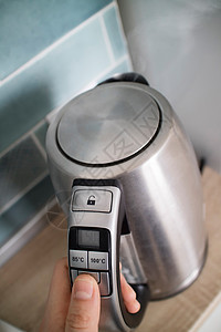 锈钢电热水壶厨房的背景上,重点放水壶的盖子上种现代多功能电水壶,可选择温度,用于同的茶厨房背景上的钢制电水背景图片