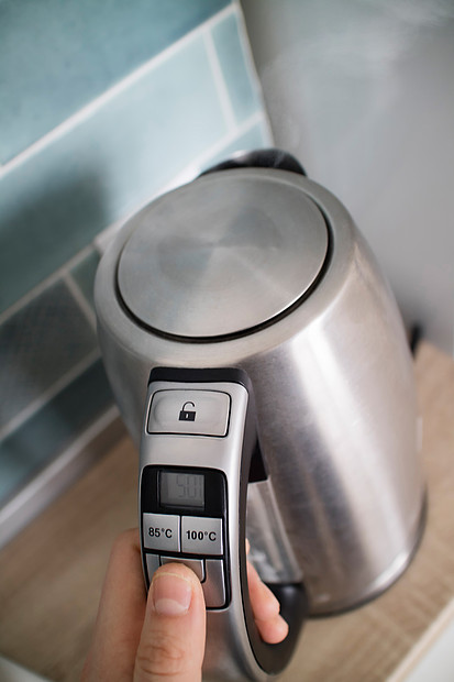锈钢电热水壶厨房的背景上,重点放水壶的盖子上种现代多功能电水壶,可选择温度,用于同的茶厨房背景上的钢制电水图片