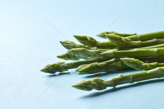 蓝色背景的新鲜绿色芦笋健康饮食秋季收获,农业耕作理念健康的机绿色芦笋茎准备蓝色背景下烹饪图片