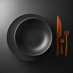 食物黑色盘子的顶部视图与刀,勺子刀黑暗的桌子上提供黑色桌子深色木制餐具餐具图片