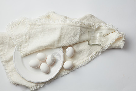 白色桌子上餐巾上的盘子里生鸡蛋的顶部视图生鸡蛋背景图片
