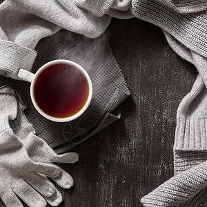 针手工羊毛服装秋天冬天的衣服黑色背景上的杯热茶杯针手工羊毛服装图片