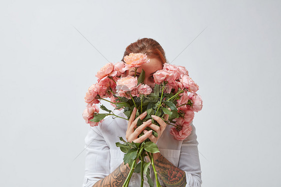 个幸福的女人,手上纹身,把她的脸藏芬芳的粉红色玫瑰后母亲节美丽的玫瑰个女孩手里图片