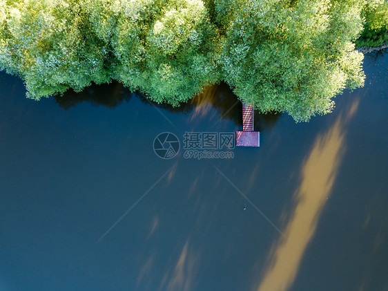 夏天的白天,森林中的湖泊上,用带阳光的木桥俯瞰湖无人机的照片城市公园湖上的空木墩上看美丽的景色图片