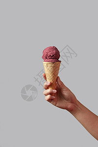 浆果红色冰淇淋的形式的球华夫饼锥,这由个女人的手灰色的背景夏季与只女手着红色浆果冰淇淋华夫饼锥图片
