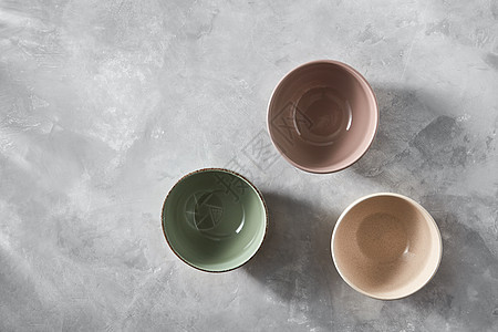 三个彩色瓷器手工陶碗孤立石灰色背景与,平躺三个五颜六色的瓷碗孤立石灰色的背景上,平躺着图片