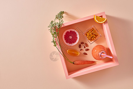 天然成分的健康冰沙胡萝卜,柑橘,杏仁沙棘璃上素食健康饮食的柑橘类蔬菜冰沙与浆果坚果个橙色的纸背景方形图片