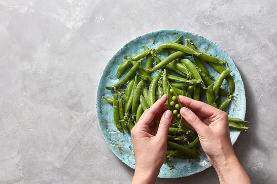 机新鲜采摘的绿色蔬菜,用于准备素食健康食品梨棒灰色混凝土桌子上的蓝色陶瓷板上,平躺女的手打开轻的豌豆图片