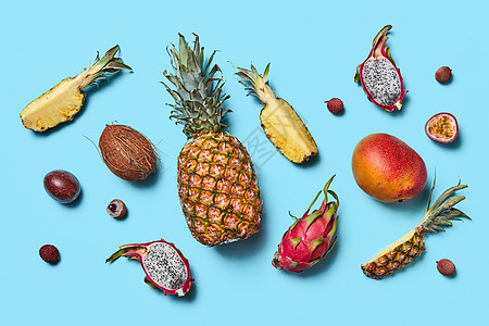 种热带水果的集合,整个半的芒果,菠萝,火龙果,椰子,荔枝蓝色背景平躺许多同的异国水果整体半呈现蓝色的背景图片