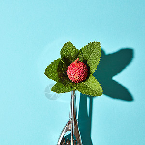 创意构图荔枝水果与薄荷叶金属勺子冰淇淋蓝色璃背景与阴影食物现代风格,俯视图平放的勺子冰淇淋与荔枝水果薄荷叶蓝色图片